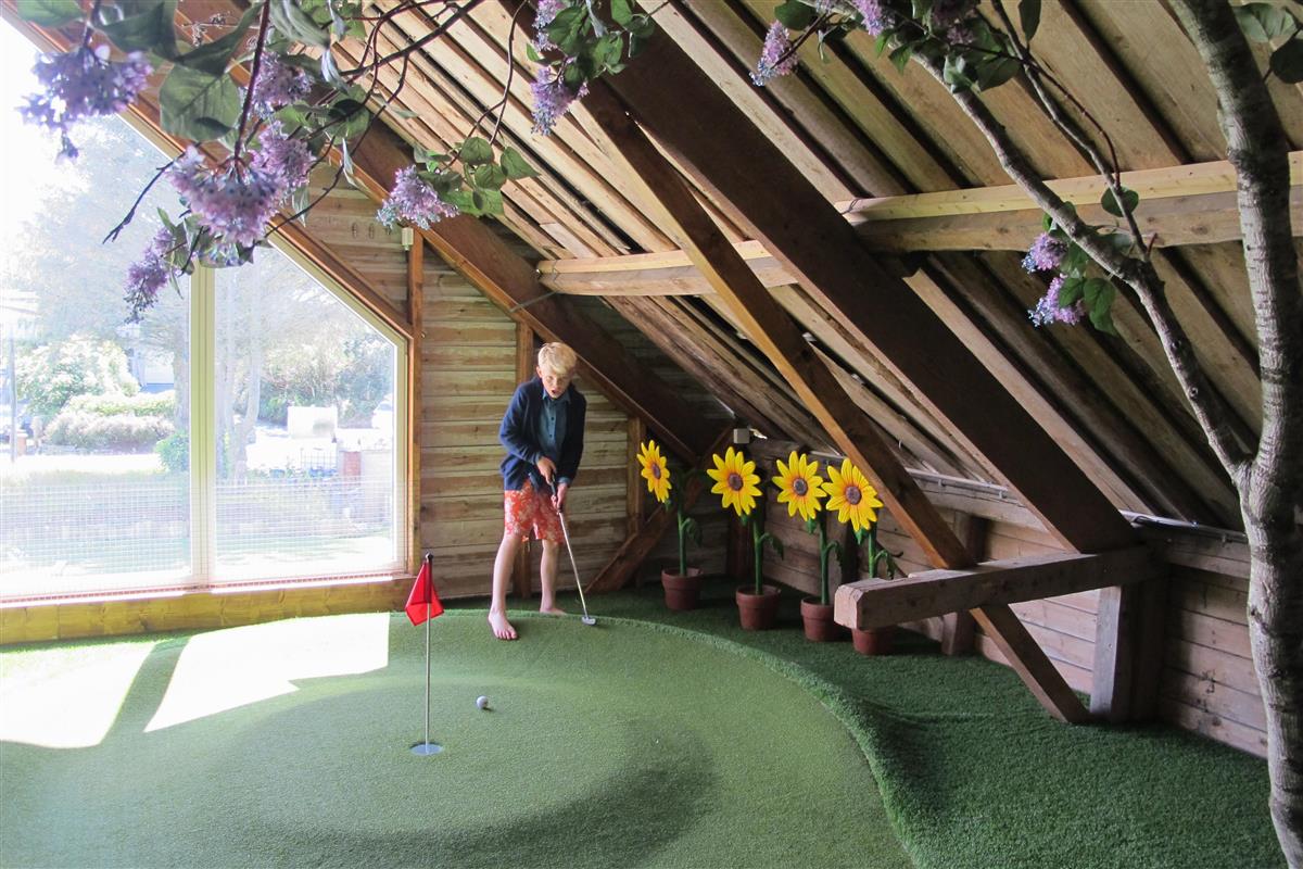 Gutt som spiller minigolf inne på låve - Klikk for stort bilde